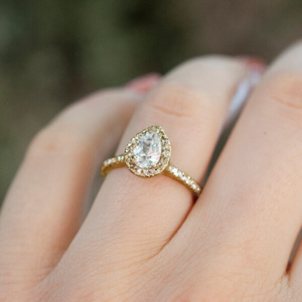 Aro Mónaco una joya de Compromiso con un Halo Pavé en Oro amarillo adornado por una piedra preciosa en la mano de la modelo