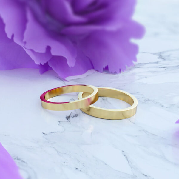 Anillos en oro amarillo de 18k de matrimonio modelo modernos en posición horizontal en fondo de flor